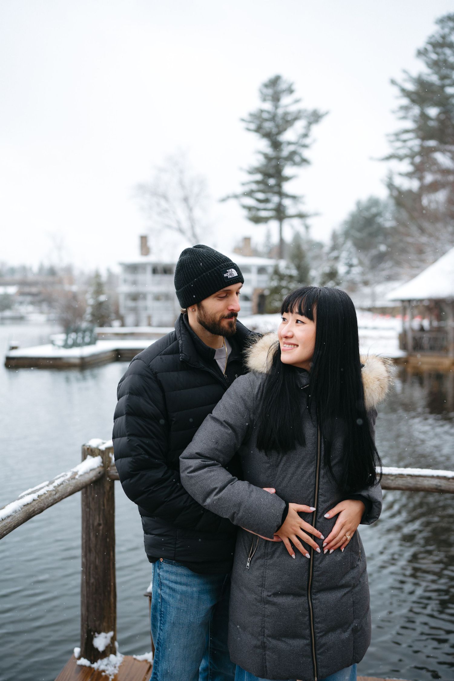 A couple sharing a joyful moment together on a snowy dock by a lake.