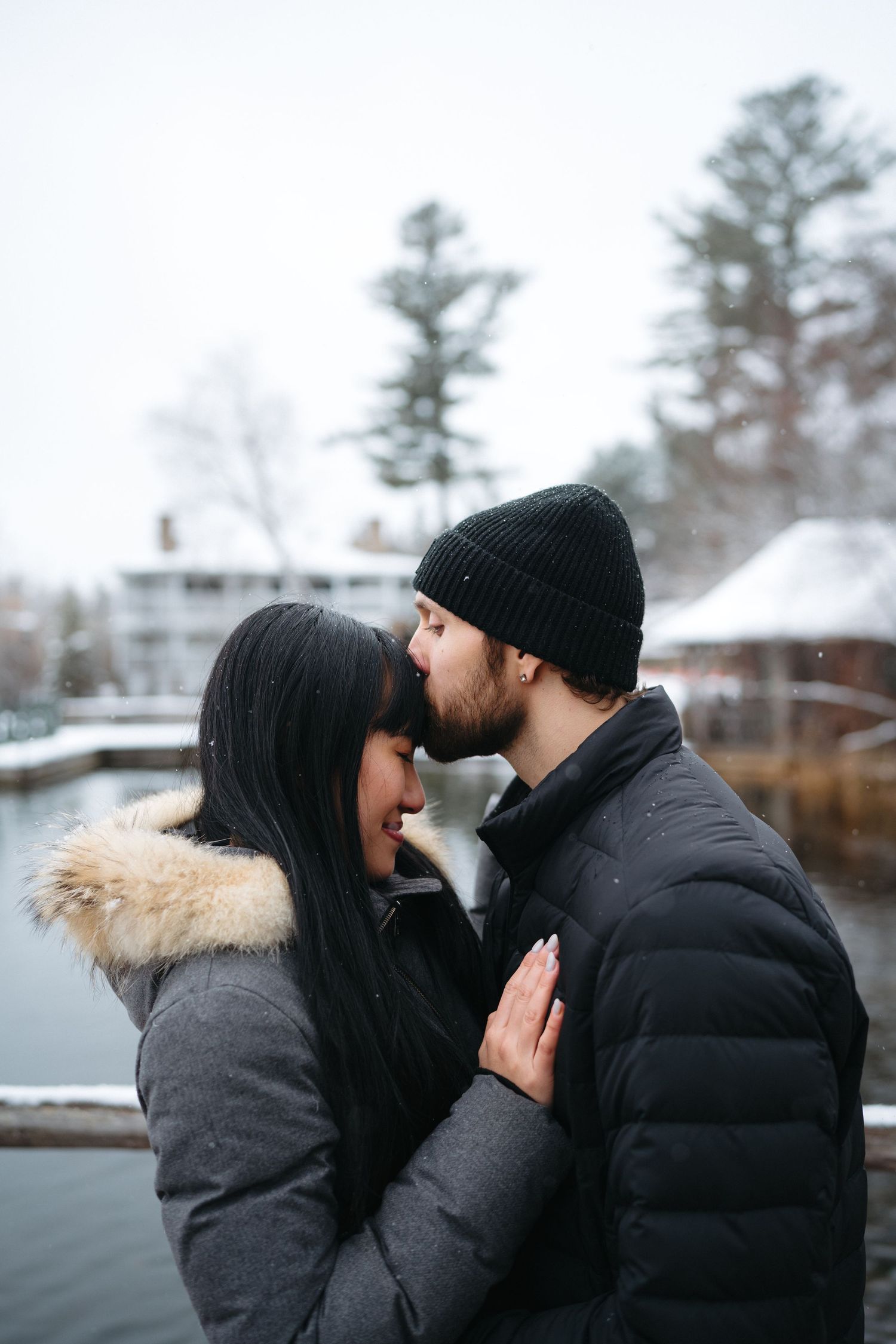 Romantic winter scene of a couple sharing an intimate moment by a snowy lake.