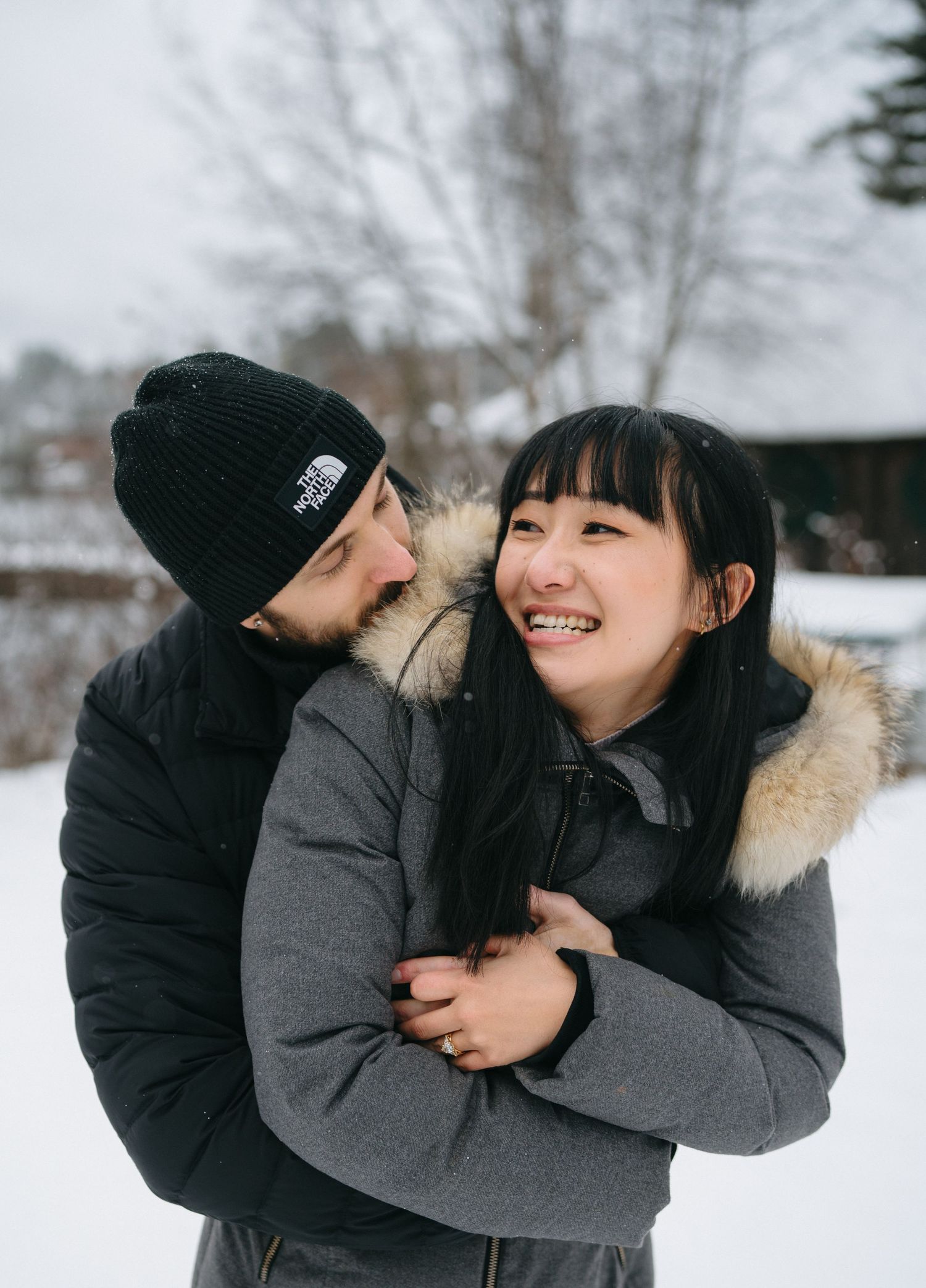 A joyful winter embrace captured between two people in cozy winter coats.