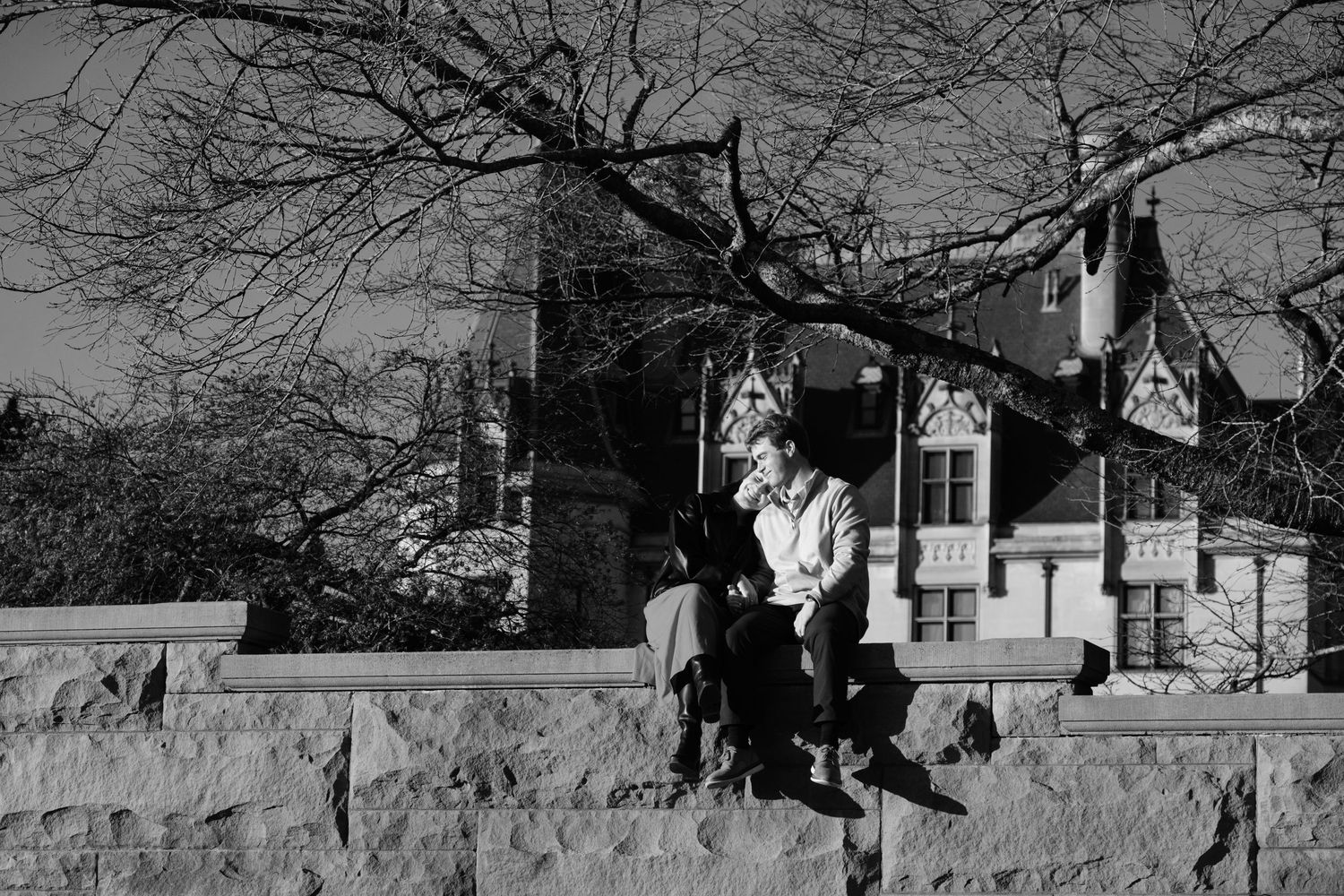 Candid Moment of Newly engaged couple hanging out on the historic wall outside of the Biltmore Estate