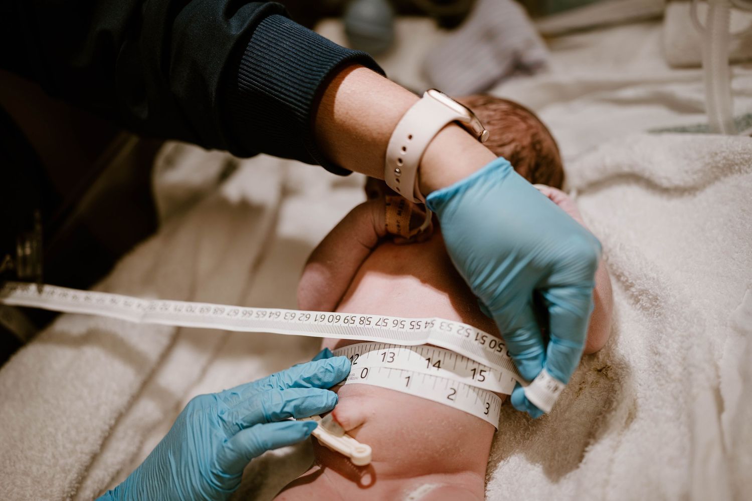 Healthcare provider measuring patient's neck with measuring tape during medical examination.