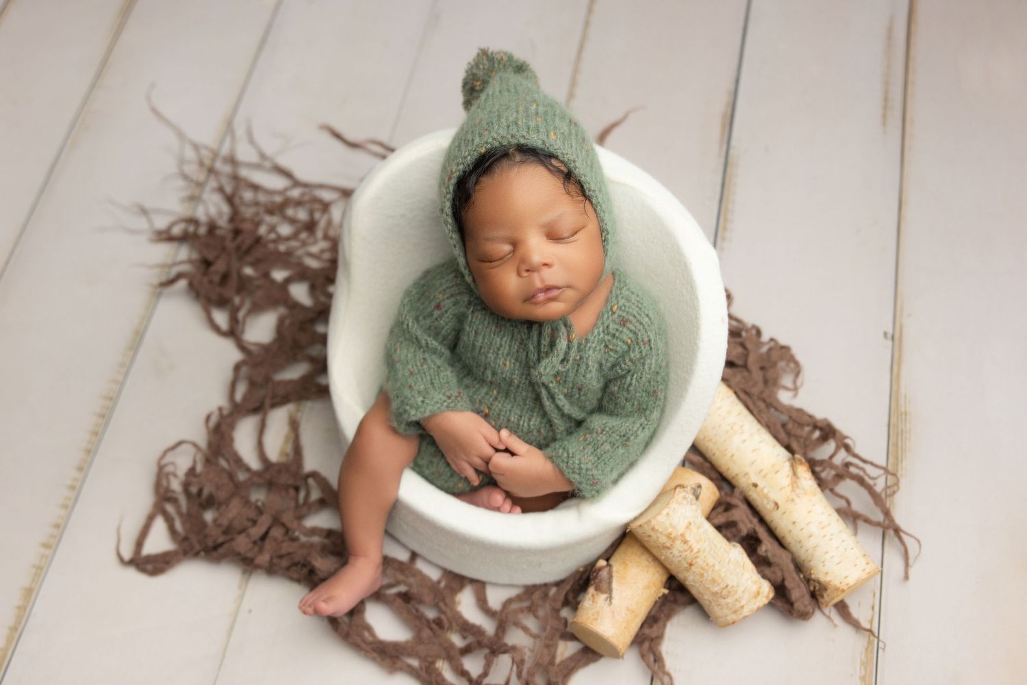Artistic newborn photography collage showing six poses of a baby in yellow against dark backgrounds with floral elements.