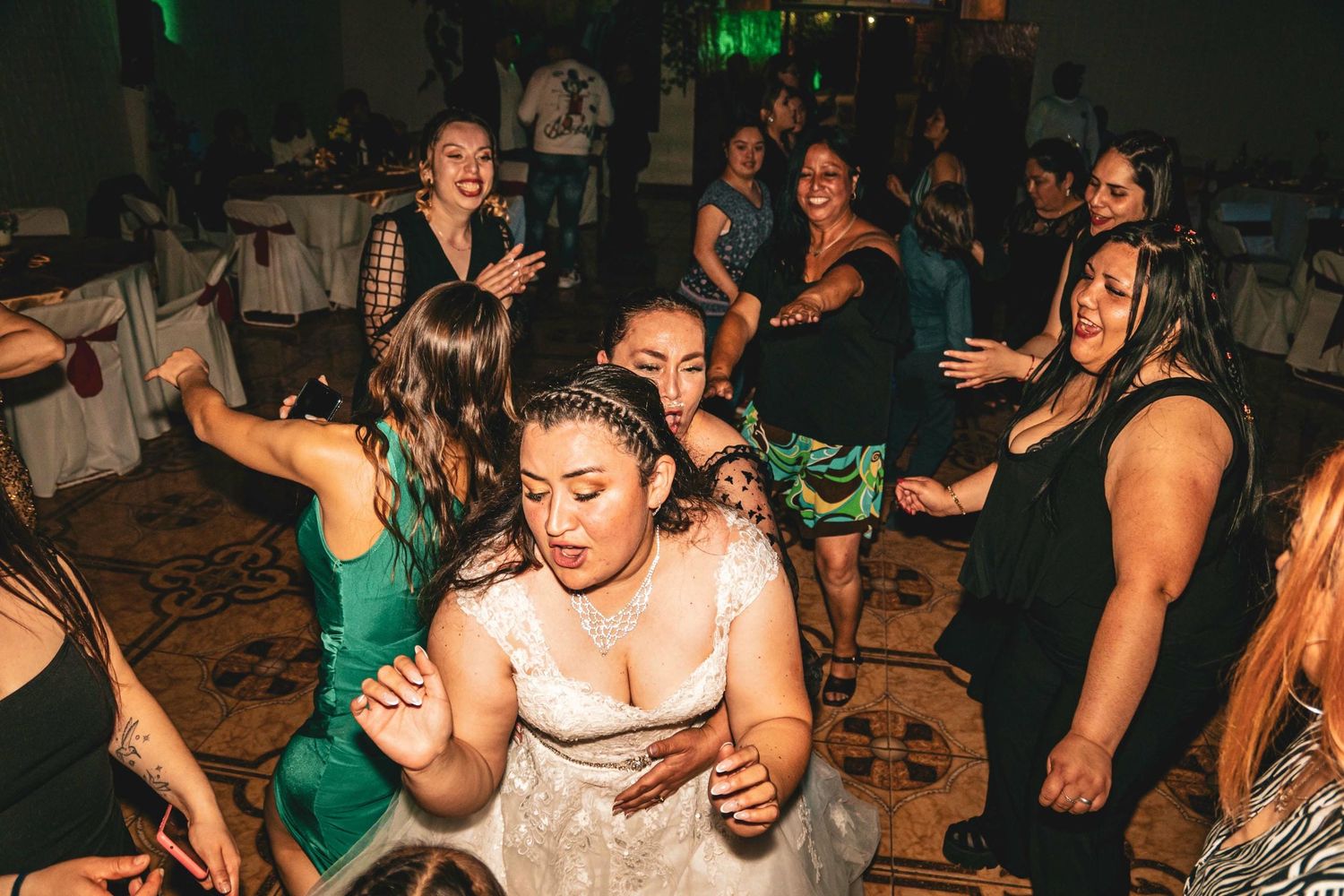 Fiesta de baile en recepción de matrimonio con invitados bailando en espacio oscuro con luces verdes.