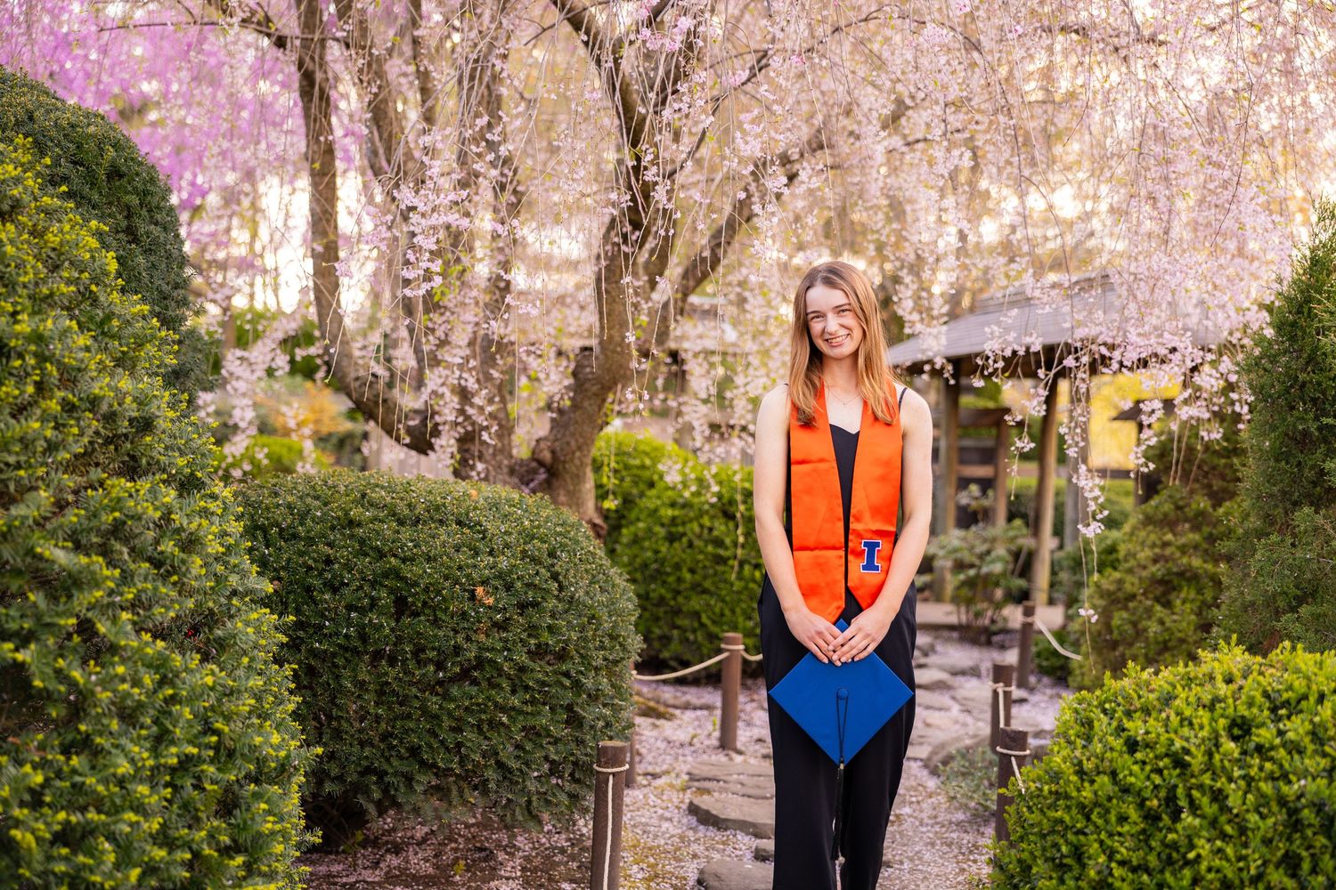 Girl with UIUC graduation attire standing and smiling at Japan House