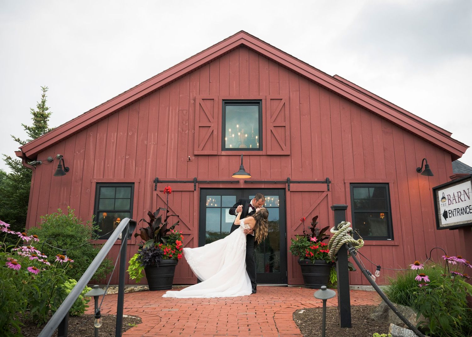 A romantic autumn wedding photo under a wooden pergola as a flowing white veil catches the breeze.