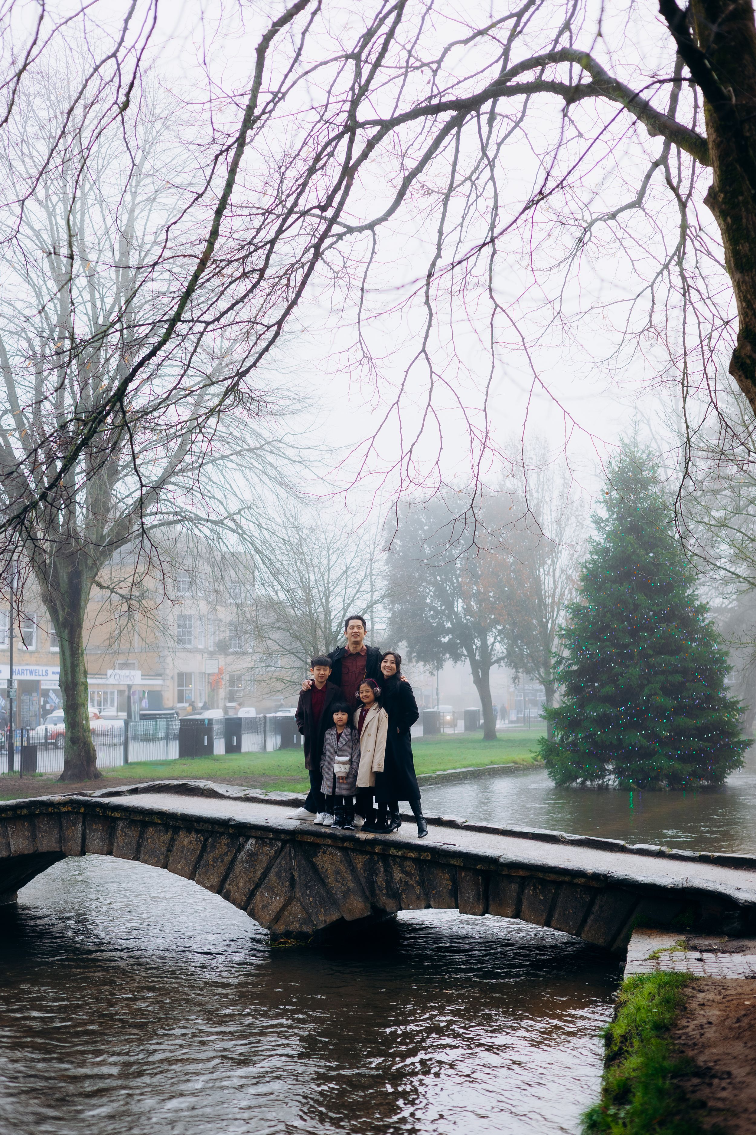 Cotswolds family photographer capturing portraits by the river in Bourton-on-the-Water.