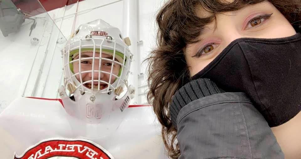 Hockey players and supporters gather for photos in sports equipment.