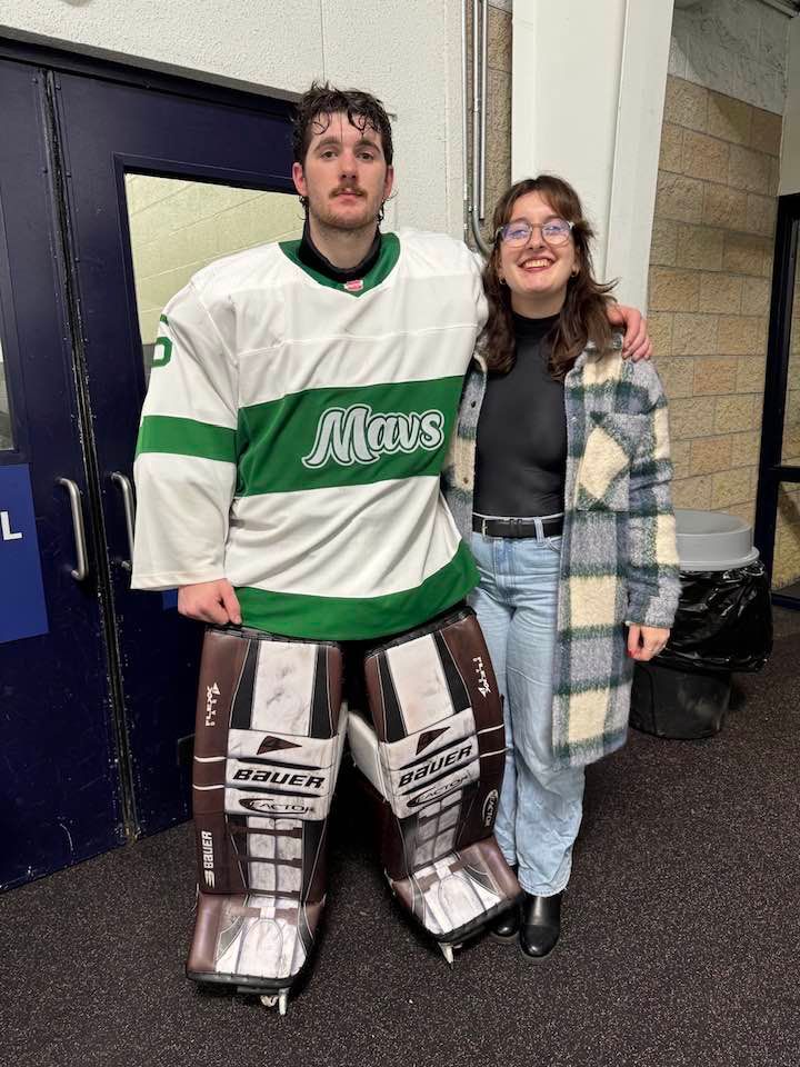 Hockey players and supporters posing together near locker room entrance.