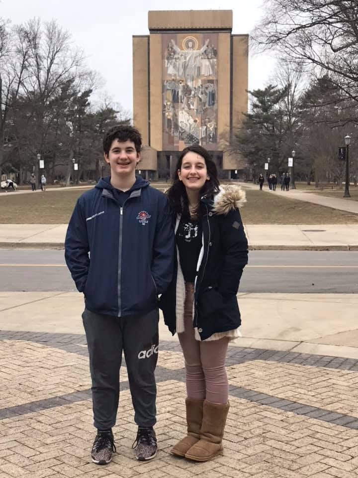 People standing outside a large building with architectural features on a winter day.