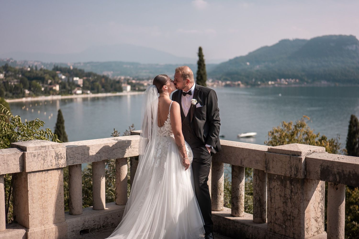 Brautpaar küsst sich auf einer Terrasse mit Blick auf den Gardasee in Bardolino bei Sonnenuntergang. Fabio Marras Hochzeitsfotograf