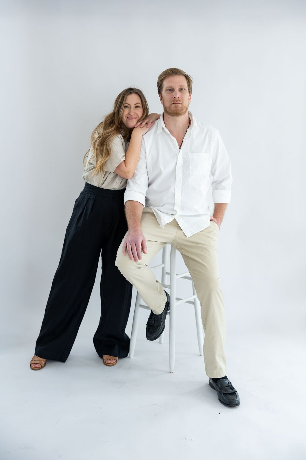 A couple in contrasting black and white outfits pose together against a white backdrop in a creative photoshoot series.