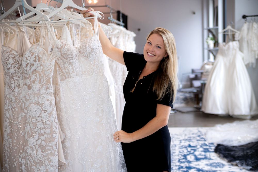 A bridal boutique interior showcases elegant white wedding dresses hanging on display racks against light walls.