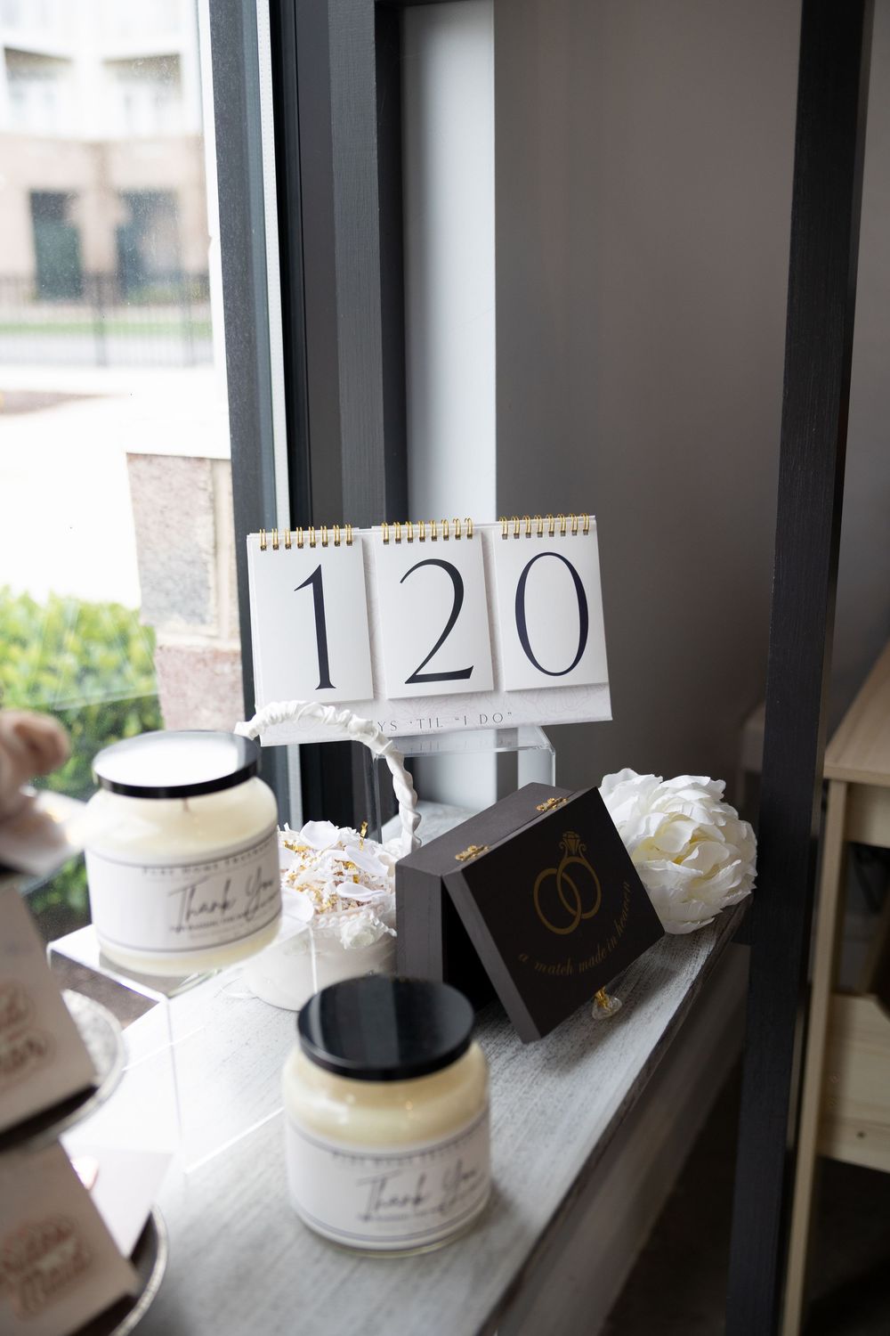 White ceramic cake stands with order numbers displayed on a window ledge in a bakery setting.