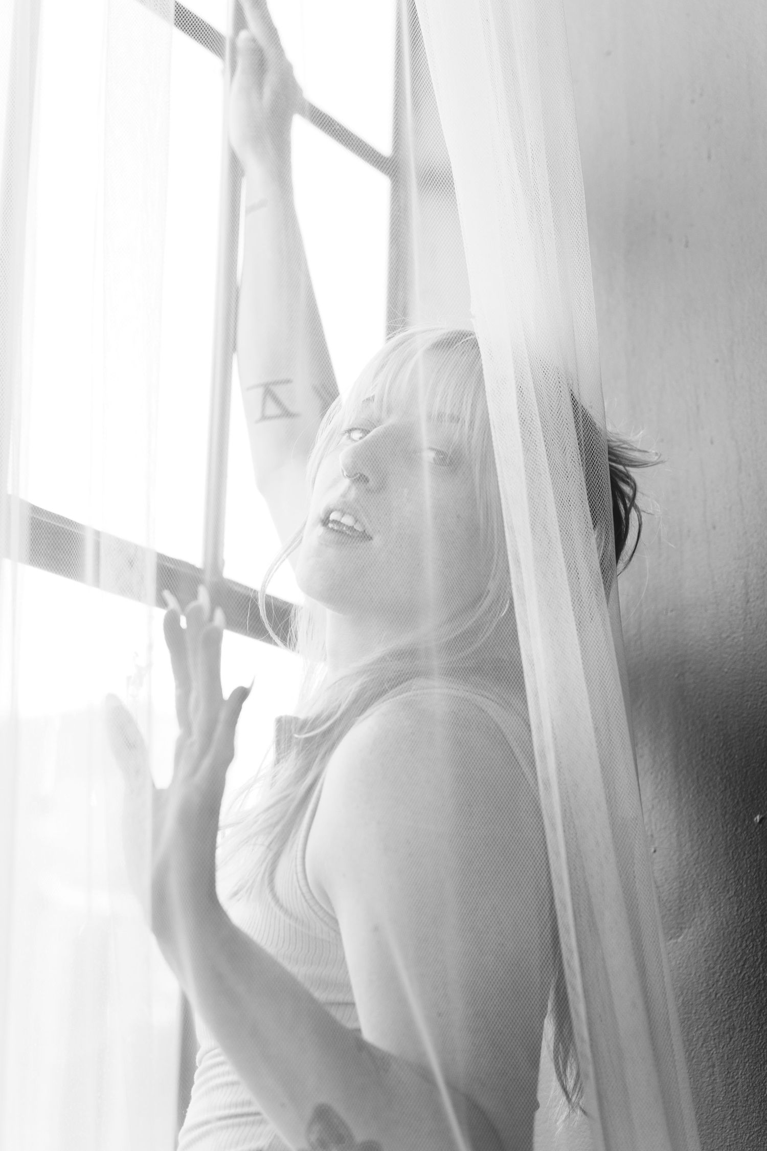 Black and white portrait of joy by sunlit window.