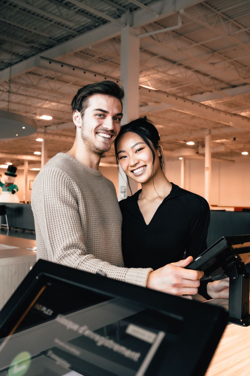Two coworkers smile while looking at a screen together in an office space.Mtlshutter photography