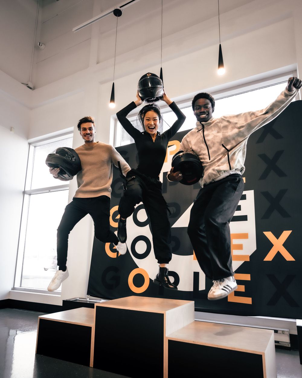 Three people jumping in celebration against a wall with text graphics. Mtlshutter photography