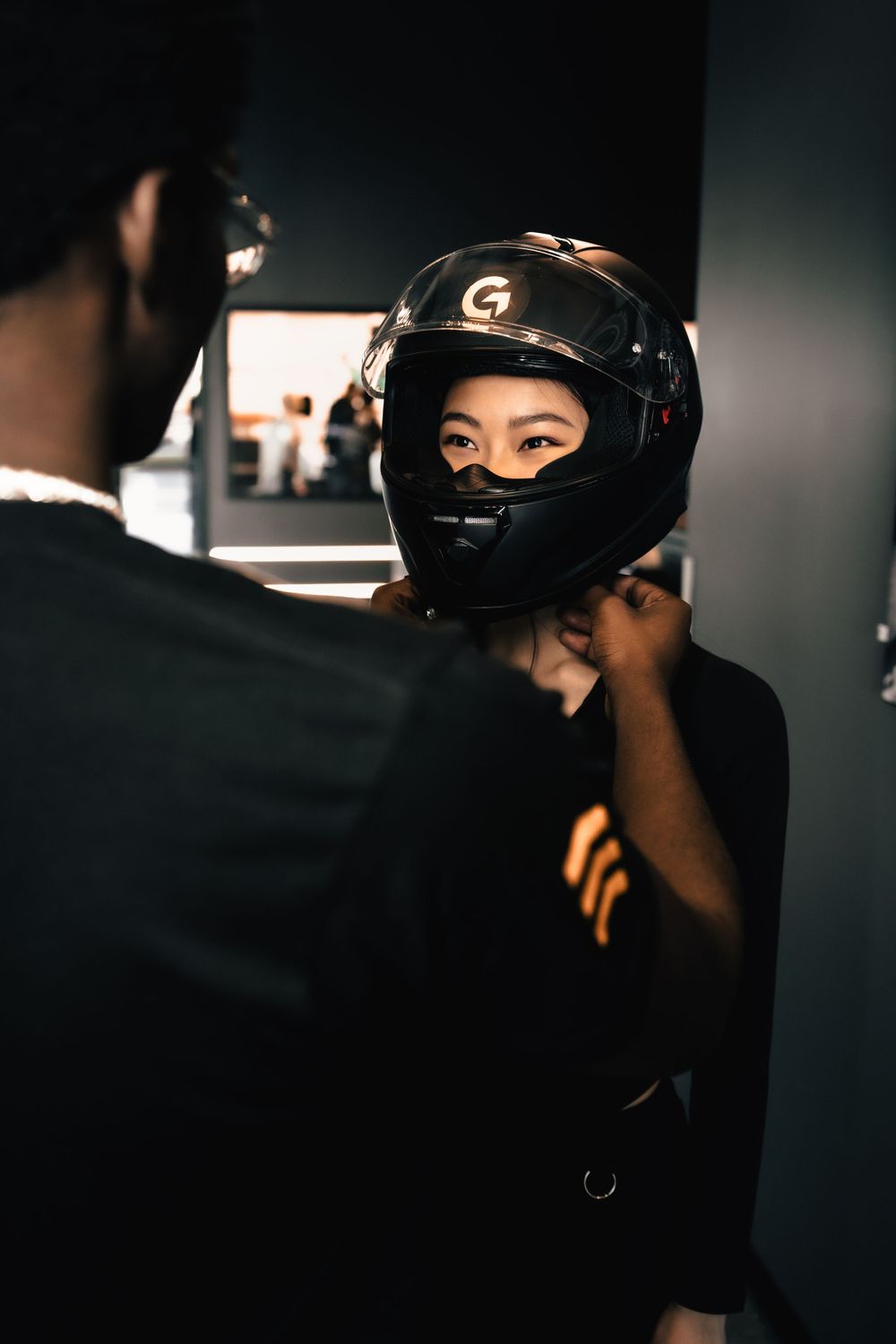 Person wearing a black gaming helmet being fitted by another person in dark lighting. Mtlshutter photography