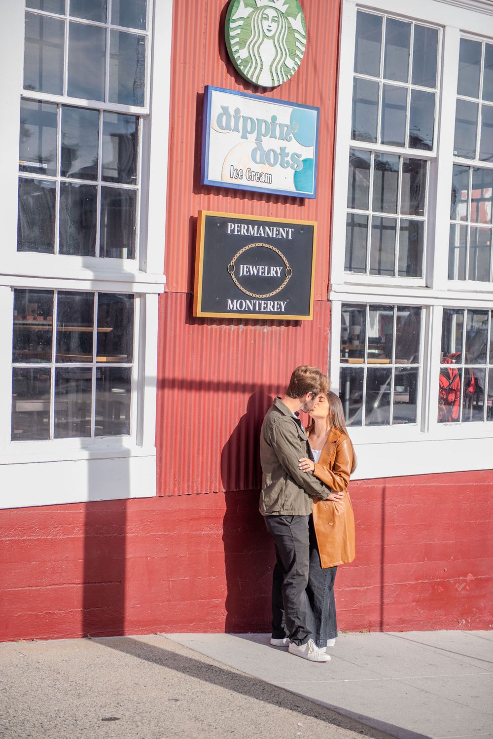 Couple sharing tender moment outside red Starbucks building in Monterey.
