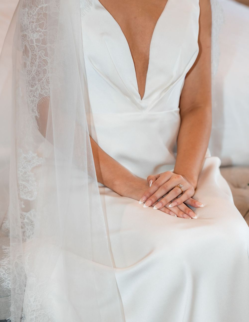 Close-up details of an elegant white wedding dress with delicate lace trim and soft fabric texture.