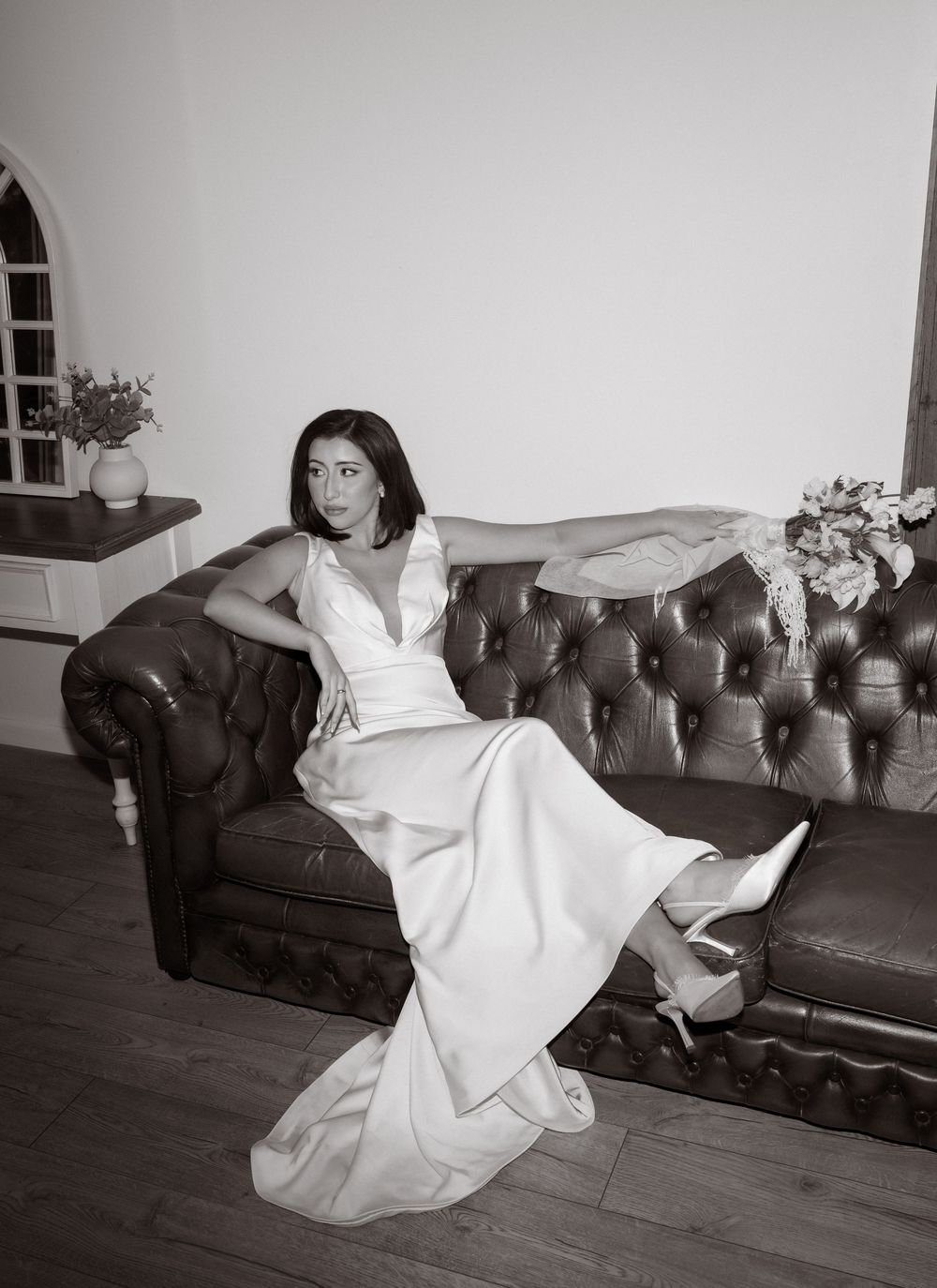 A sequence of black and white photos showing a person in a white dress floating and falling on a vintage chaise lounge.