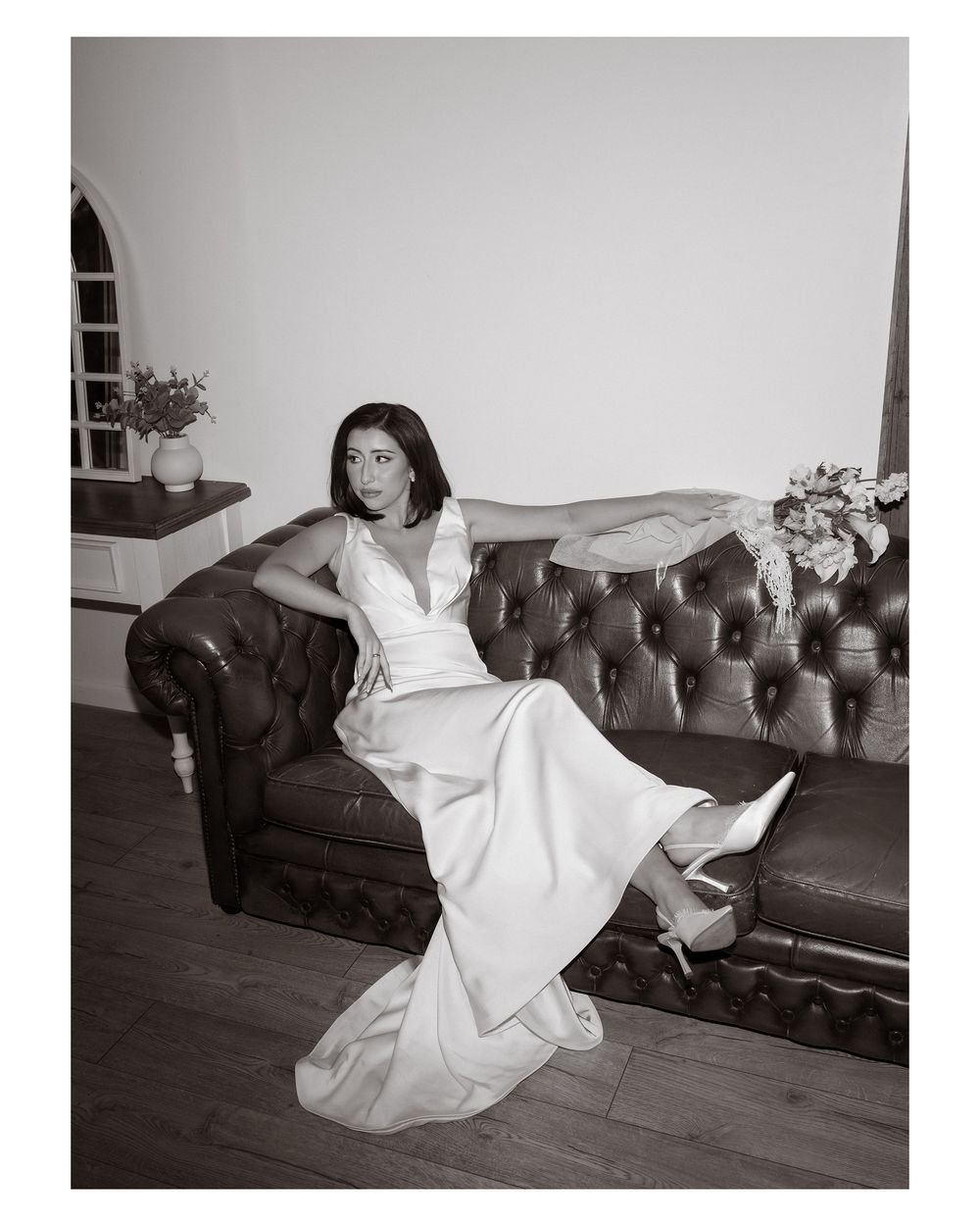 A sequence of four black and white photos showing someone in a white dress reclining on a dark sofa.