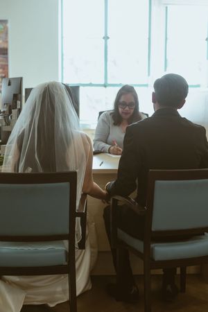 Couple meets with officiant at desk for wedding paperwork and documentation.