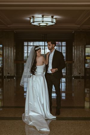 Romantic wedding portraits captured in a grand lobby with art deco style lighting and columns.