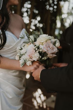 Close-up of delicate pink and white bridal bouquet with roses against dark background.