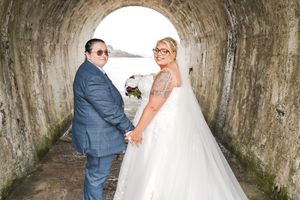 Couple poses together in a rustic stone passage with archways creating a romantic wedding photo atmosphere.