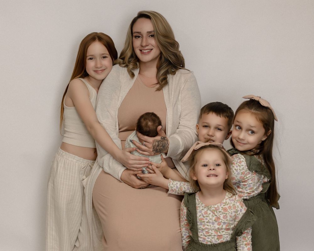 Family portrait in neutral tones with beige and cream clothing against minimal studio backdrop.