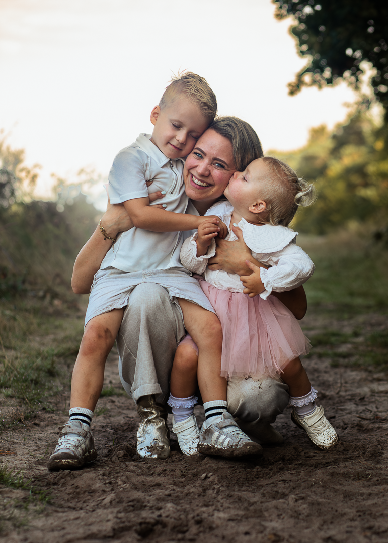 Moeder met twee kinderen knuffelen in het bos.