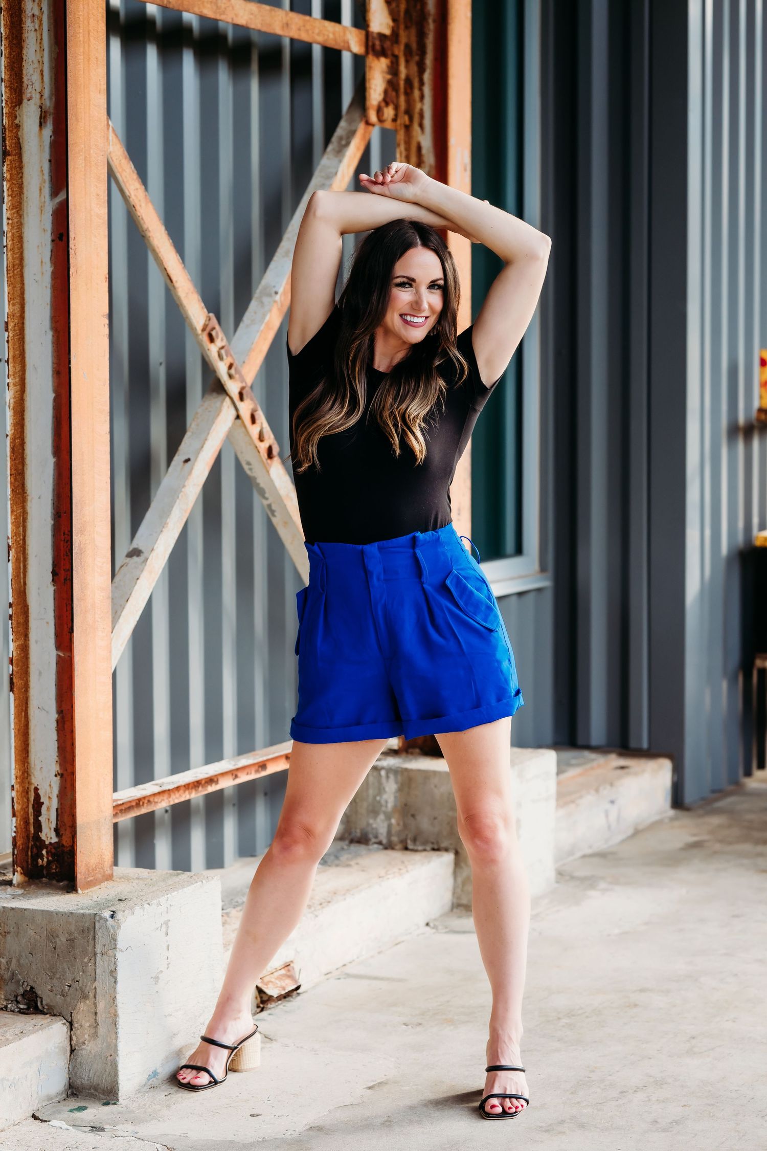 Dynamic poses of someone wearing bright blue shorts and a black top against an industrial background.