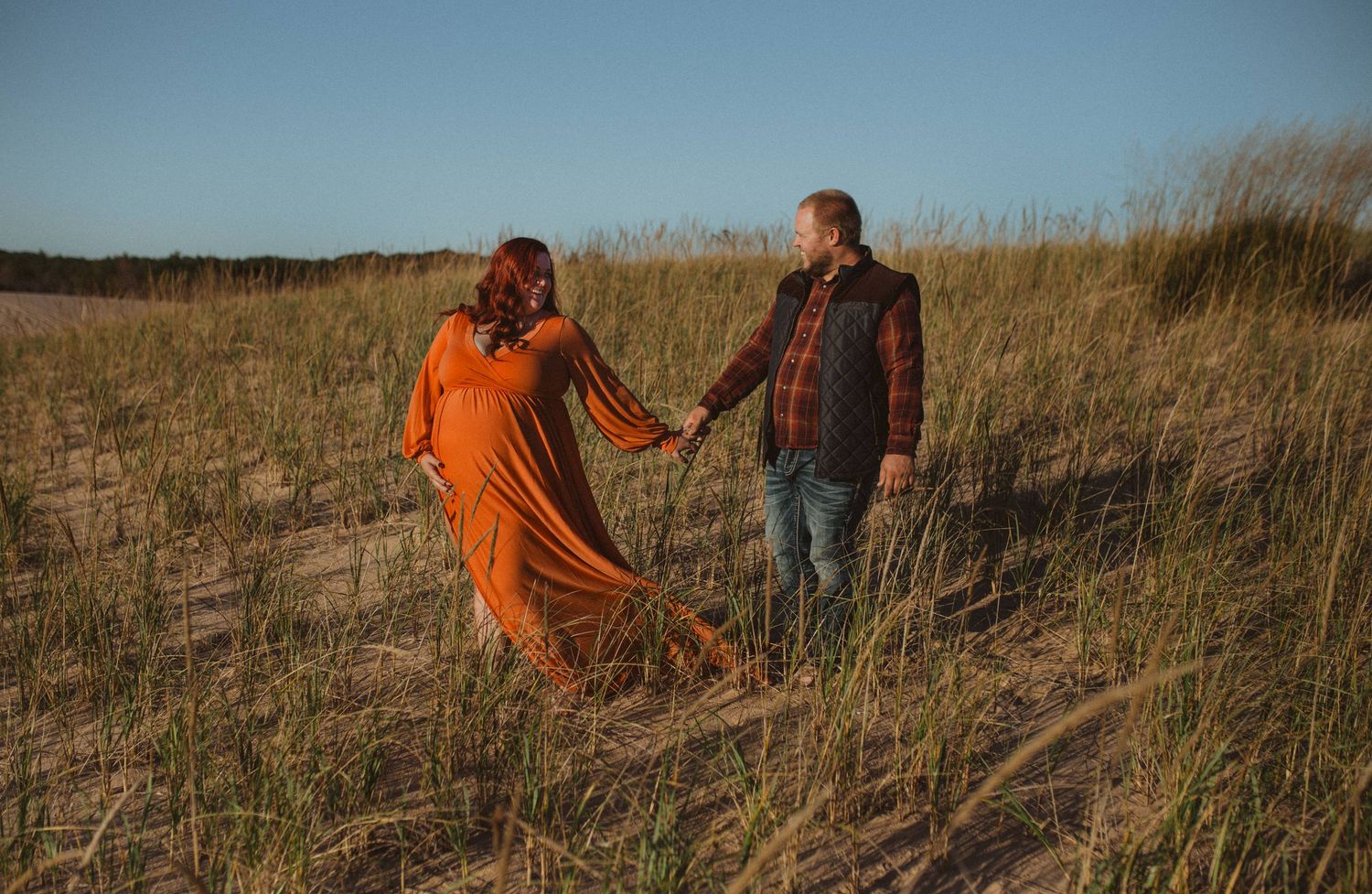 Artistic photography sequence on sand dunes with orange dress flowing in natural light.