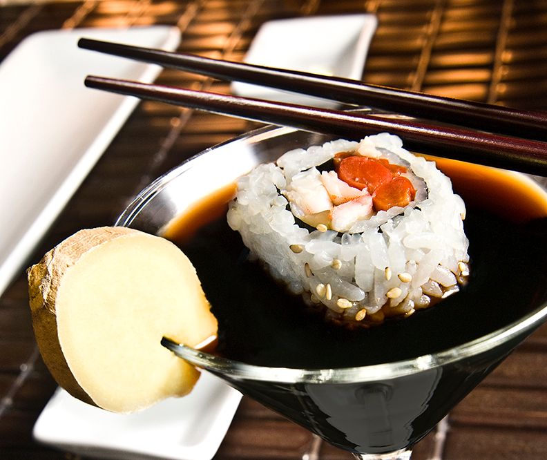 A California sushi roll with salmon and cream cheese served in a martini glass with soy sauce and fortune cookie.