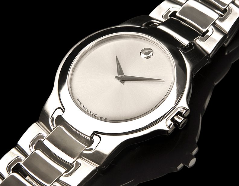 Elegant silver Movado women's watch with minimalist round dial and classic metal bracelet design on black background.