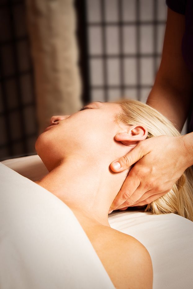A client receives a relaxing neck and shoulder massage at a spa treatment room with rice paper screens in the background.