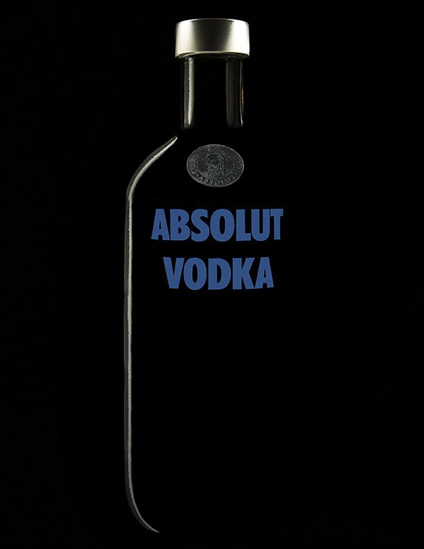 A dark bottle of Absolut Vodka with blue lettering photographed against a black background.