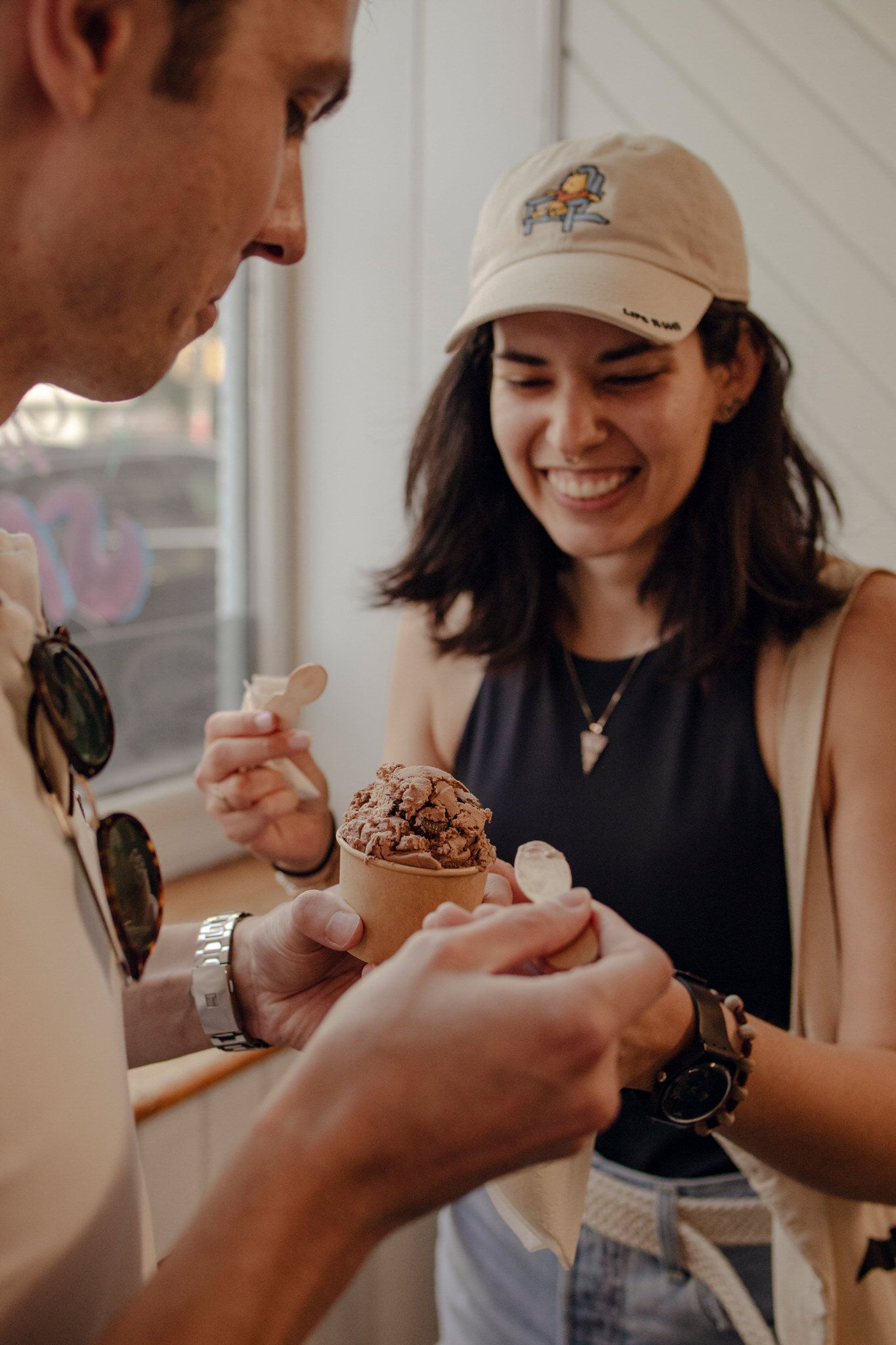 Playful couple sharing chocolate ice cream during a candid portrait session at a downtown Kingston ice cream shop, White Mountain.