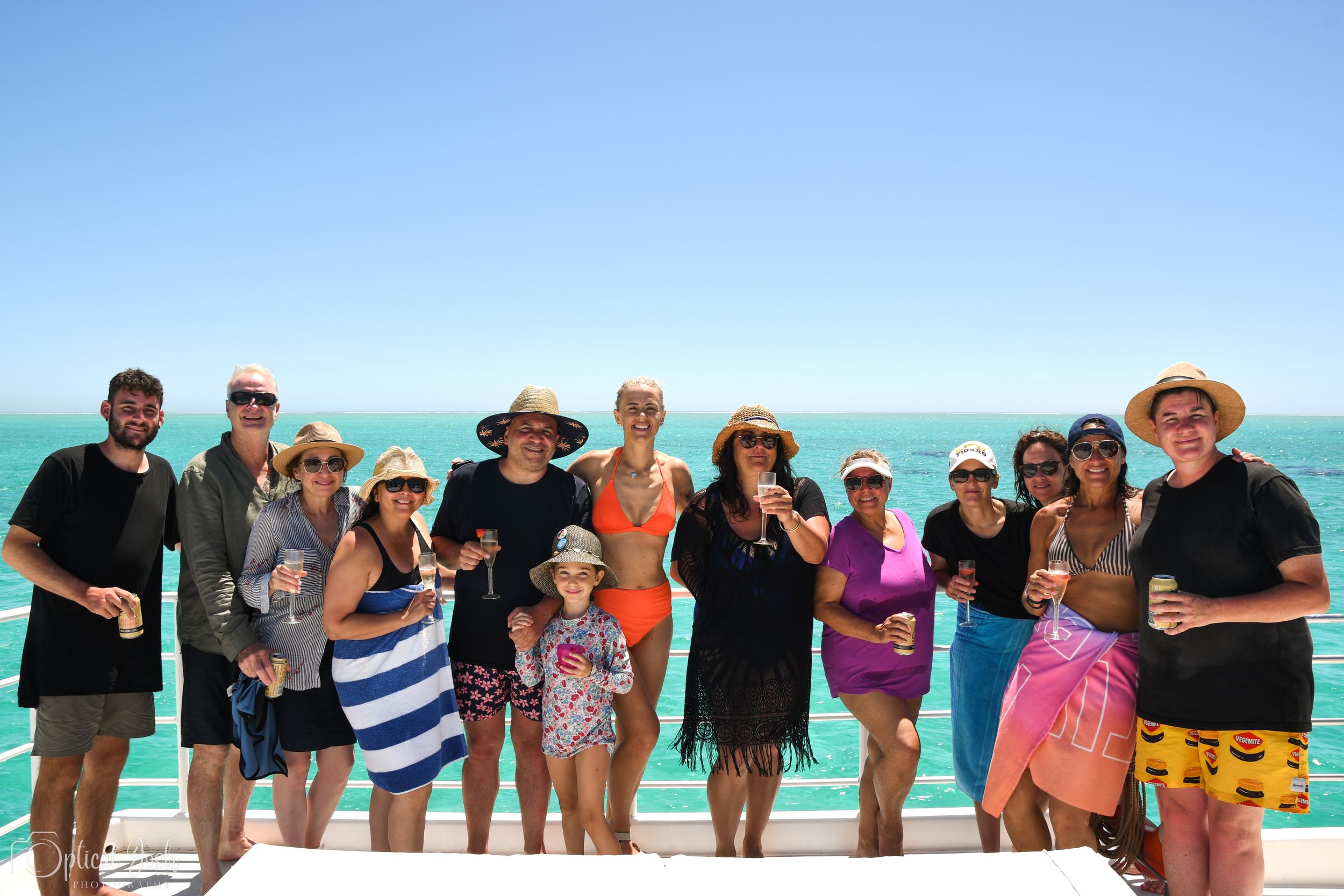 Group of friends enjoying a sunny beach day together with turquoise ocean waters in the background.