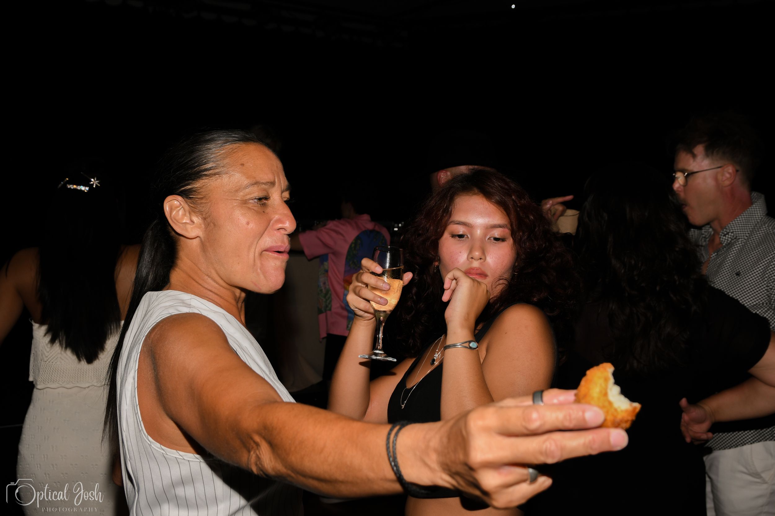 People enjoying drinks and snacks while dancing at a dark nightclub party.