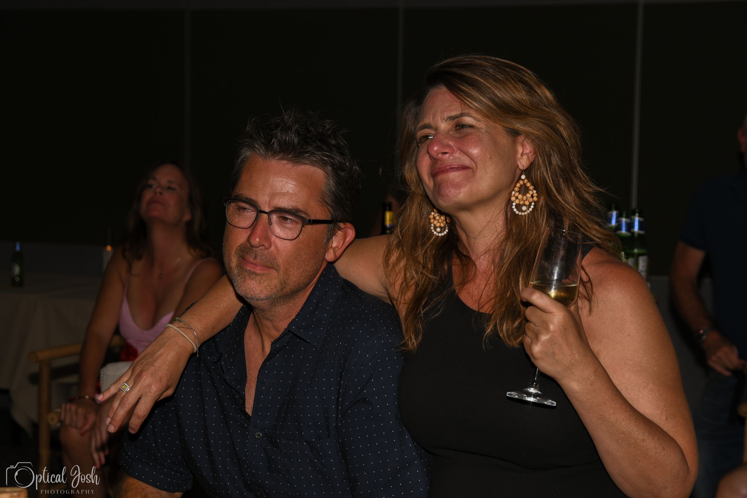 Two people sitting together and enjoying themselves at a dark indoor venue.