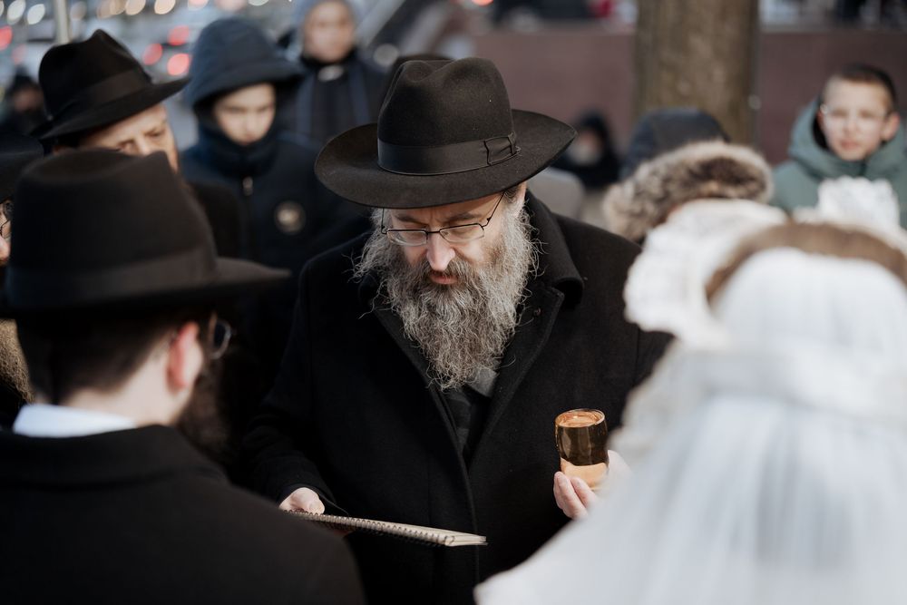 Orthodox Jewish ceremony with men in traditional black attire gathered around.