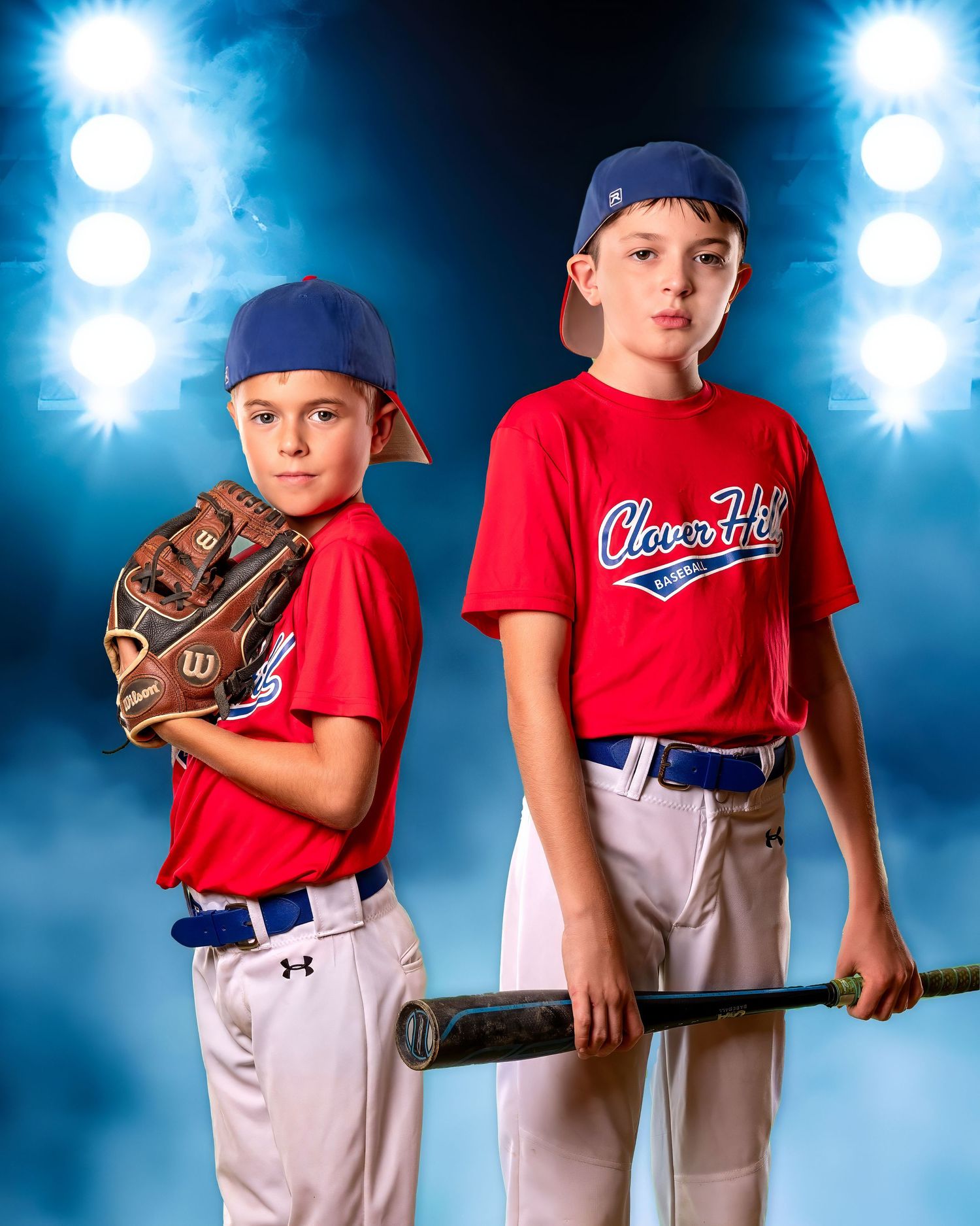 Two youth baseball players in red jerseys and navy caps pose with baseball gear against a blue spotlight background.