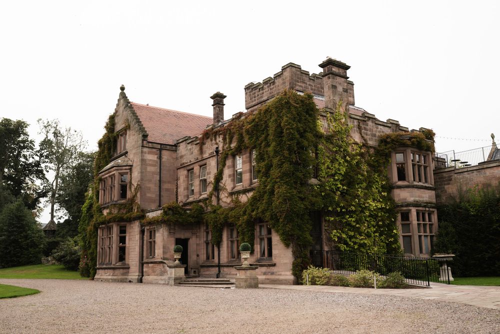 Panoramic view of a historic stone manor house with ivy-covered walls.