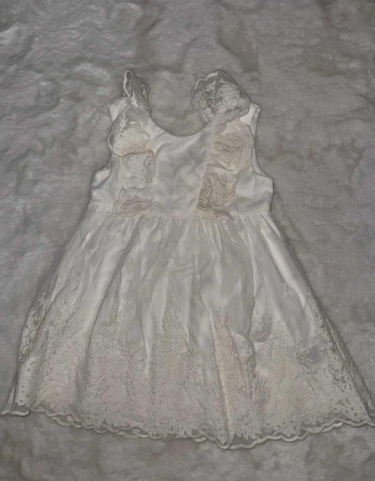 Vintage-style white lace baby dress with embroidered details on gray background.
