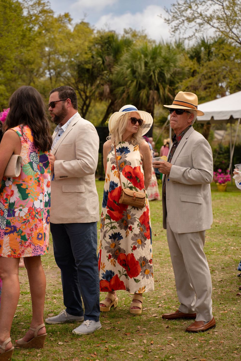 Group of well-dressed attendees mingling at an outdoor garden party.