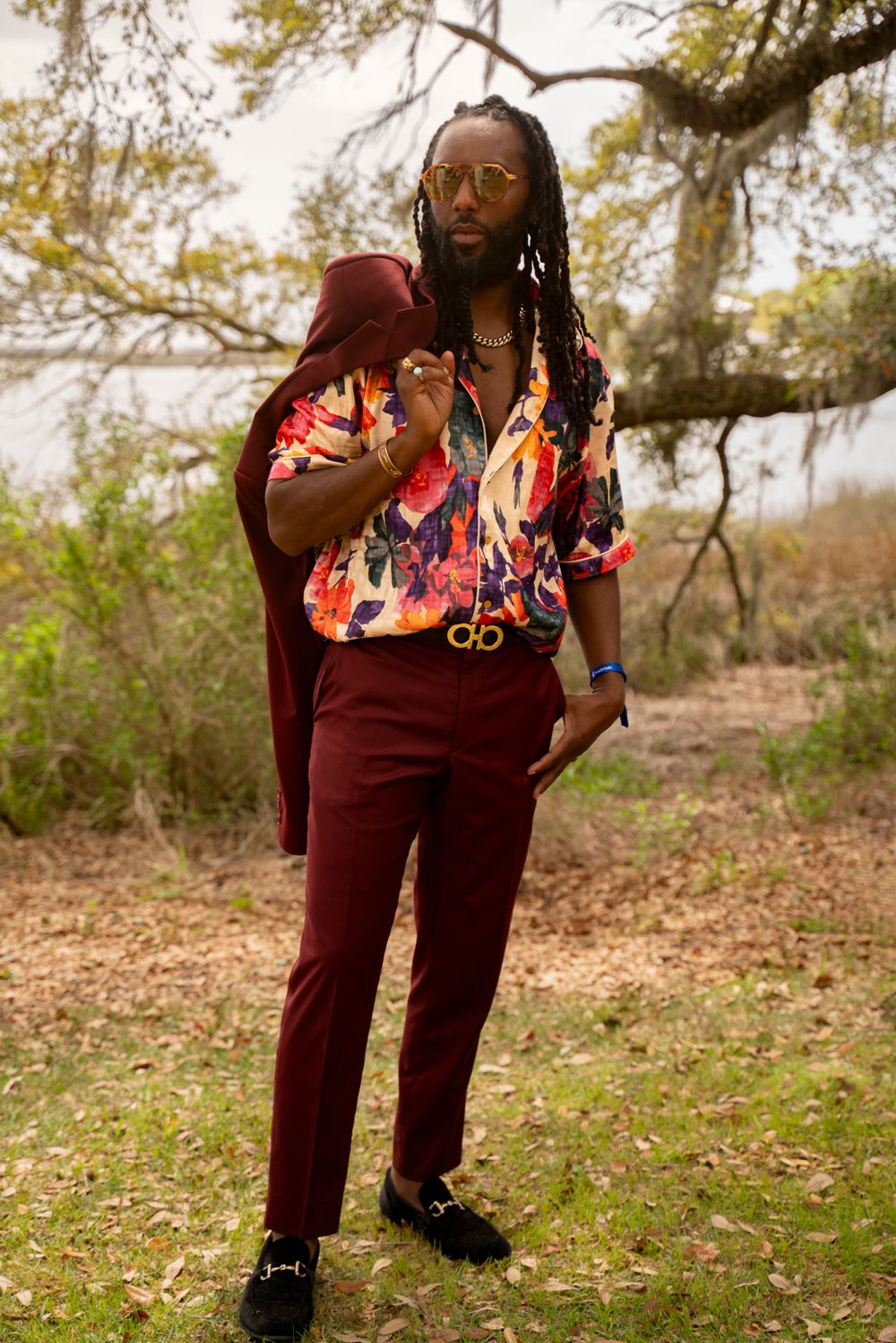 Photographer Tim Ellis posses in a floral shirt and burgundy suit strikes a pose against a natural backdrop Airlie Luncheon Garden Party.