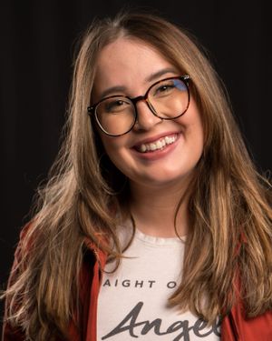 Portrait of someone with glasses and long hair wearing a casual shirt.