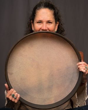 Person holding up a large frame drum with natural skin head in a studio photoshoot.