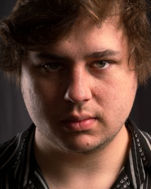 Cinematic close-up portrait of a young person with dark hair in dramatic lighting.